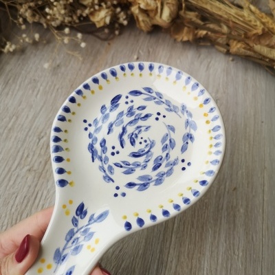 Colher de pau de cerâmica com padrão azul e amarelo e fundo de flores secas