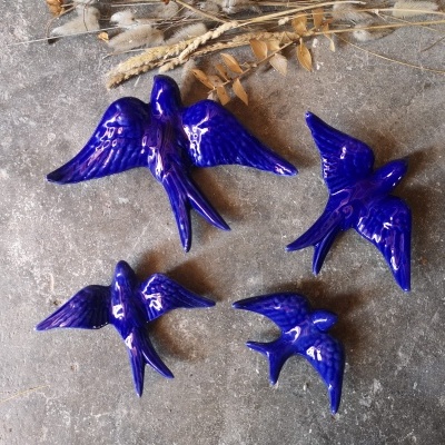 Pássaros decorativos em cerâmica azul brilhante sobre superfície cinzenta