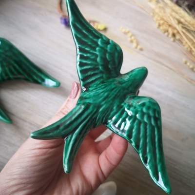 Figura cerâmica de pássaro verde com detalhes texturados nas asas