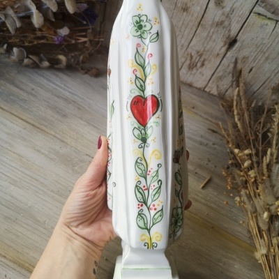 Escultura branca em cerâmica com decoração floral e coração vermelho