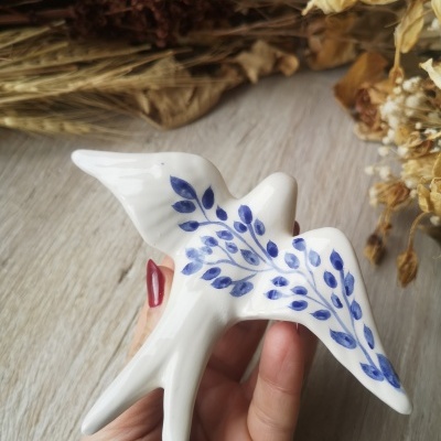 Estatueta cerâmica branca de pássaro com pintura azul nas asas
