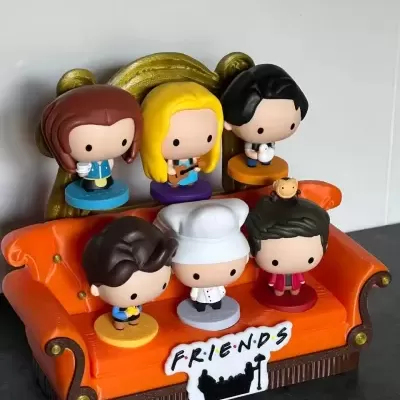 Conjunto de figuras miniatura de personagens em sofá laranja com placa FRIENDS