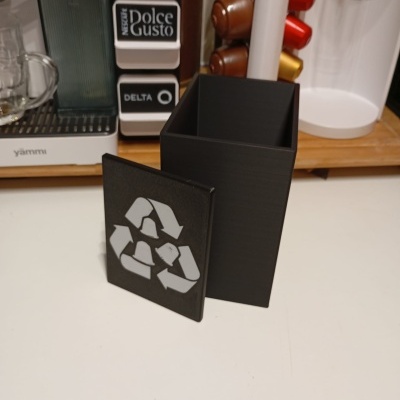 Recipiente preto com símbolo de reciclagem em cozinha.