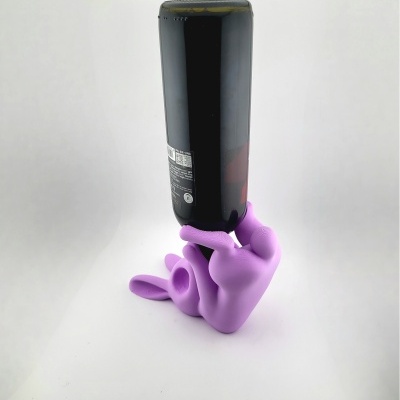 Suporte roxo de figura humana a segurar garrafa preta de cabeça para baixo.