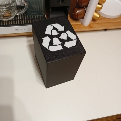 Caixa preta para reciclar cápsulas de café com símbolo de reciclagem no topo