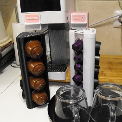 Máquina de café branca NESPRESSO com porta-cápsulas e duas chávenas de vidro numa bancada de cozinha