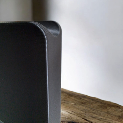 Dispositivo eletrônico preto com cantos arredondados sobre superfície de madeira rústica