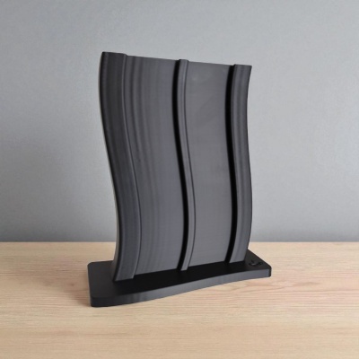 Escultura decorativa preta ondulada em base preta sobre mesa de madeira