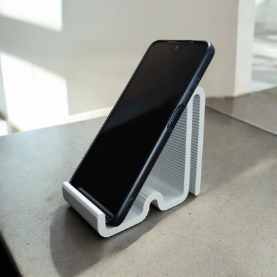 Suporte branco para telemóvel com telemóvel preto em cima de superfície de pedra.