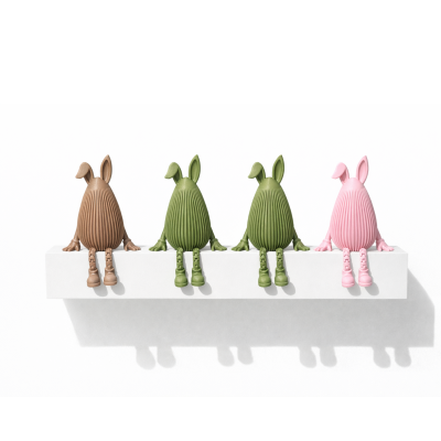 Figuras decorativas de coelhos em plástico castanho, verde e rosa sentados numa prateleira branca