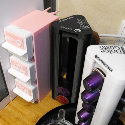 Porta-cápsulas para café Nespresso em plástico de cores rosa, preto e branco, com cápsulas roxas e laranjas.