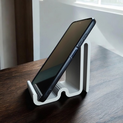 Suporte branco ondulado para telemóvel preto numa mesa de madeira