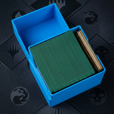 Caixa de plástico azul com cartas verdes e douradas sobre superfície preta com ícones gráficos.