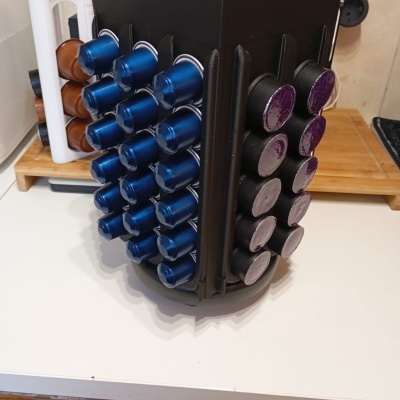 Suporte giratório preto com cápsulas de café coloridas numa bancada de cozinha