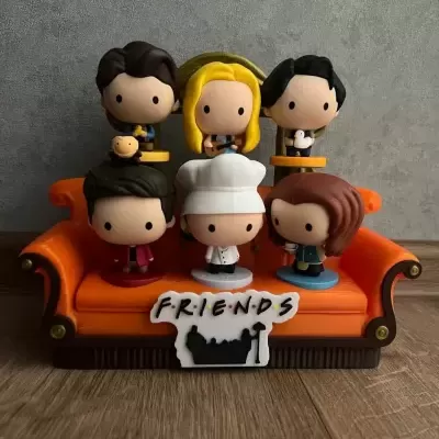 Figuras Funko Pop da série Friends num sofá laranja com placa FRIENDS.