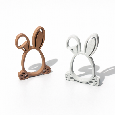 Dois suportes decorativos em formato de coelho, castanho e cinzento claro, sobre superfície branca.