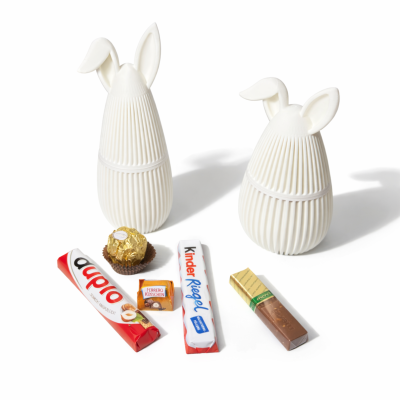 Duas caixas em forma de ovo com orelhas brancas e vários chocolates ao redor.