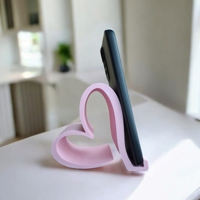 Suporte para telemóvel cor-de-rosa em forma de coração numa mesa branca