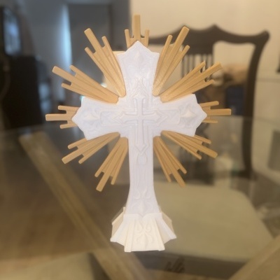 Cruz branca com raios dourados decorativos sobre mesa de vidro