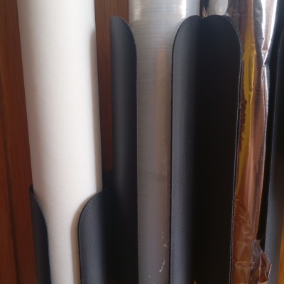 Três rolos em suportes pretos à parede em madeira