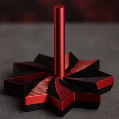 Objeto decorativo vermelho e preto com base em forma de estrela e haste cilíndrica