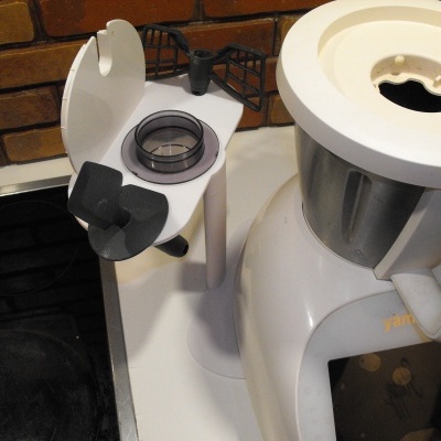 Robô de cozinha branco com jarro metálico e suporte para acessórios numa bancada de cozinha