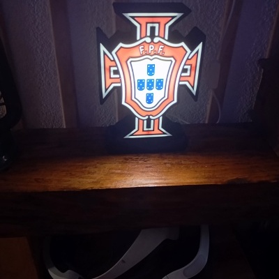 Luminária com escudo da Federação Portuguesa de Futebol em madeira e auscultadores ao fundo