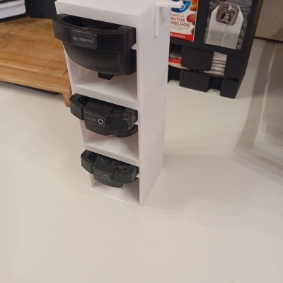 Suporte branco com três cápsulas de café rotuladas NESPRESSO, DELTA Q e CAFÉ MOÍDO