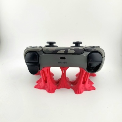 Comando Sony camuflado cinza e preto apoiado em base vermelha fluída