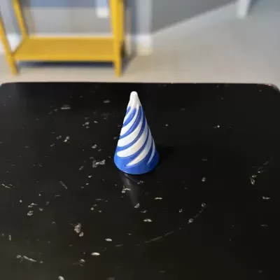 Cone decorativo azul e branco em mesa preta com móvel amarelo ao fundo