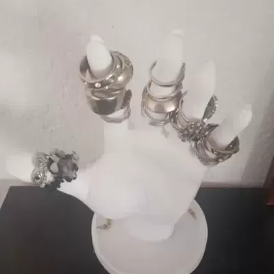 Suporte de mão branca com anéis variados de metal prateado e dourado