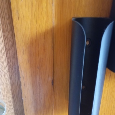 Suporte preto de parede em madeira clara com parafusos e parte de garrafa plástica