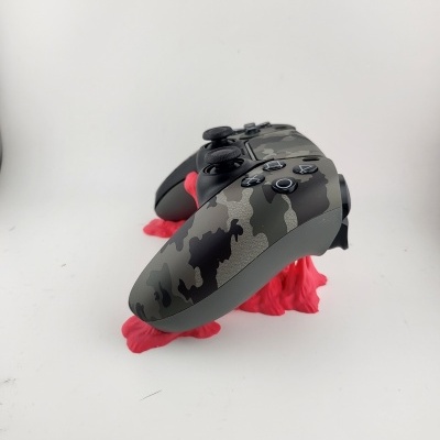 Comando de videojogo camuflado preto e cinzento com botões pretos e símbolos brancos