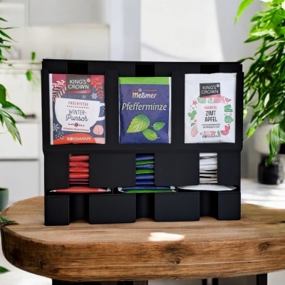 Conjunto de chás em saquetas nas cores vermelho, azul e branco organizados em suporte preto sobre mesa de madeira.