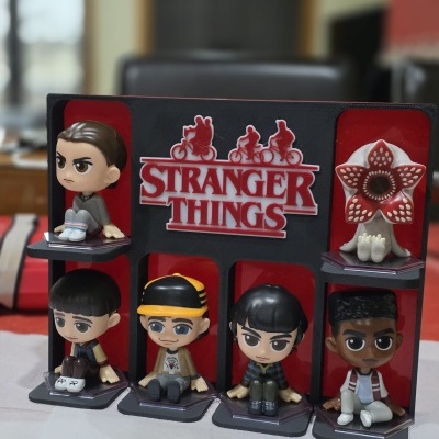 Conjunto de bonecos em PVC com personagens da série Stranger Things num suporte preto e vermelho.