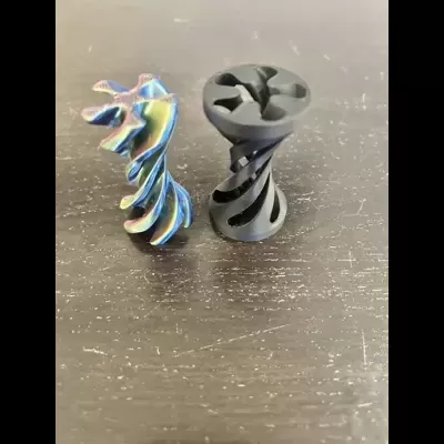 Dois parafusos espirais, um metálico iridescente e outro preto, em superfície escura