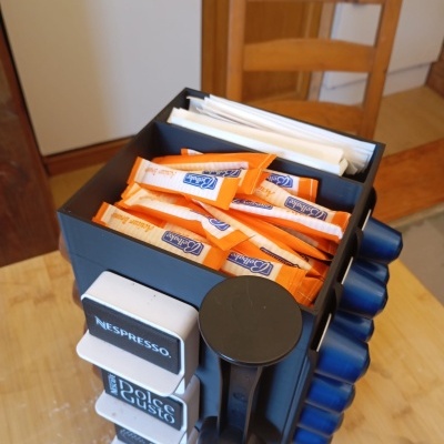 Organizador de cápsulas de café e sachês em plástico preto sobre mesa de madeira