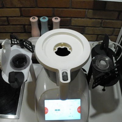 Máquina de cozinha multifunções branca com visor digital e acessórios sobre bancada.