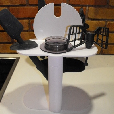 Acessórios de cozinha em plástico e borracha com espátula e suporte branco sobre superfície branca