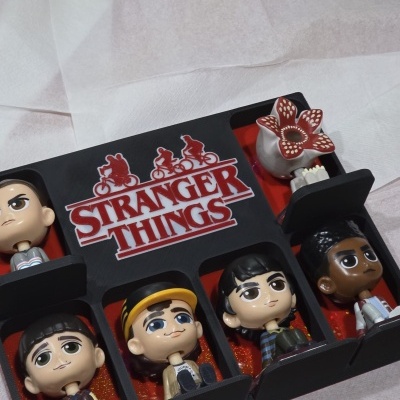 Bonecos colecionáveis da série STRANGER THINGS numa caixa preta com separadores