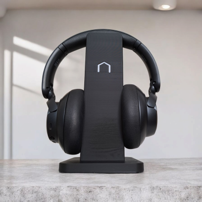 Auscultadores sem fios negros numa base preta de carregamento sobre uma mesa cinzenta