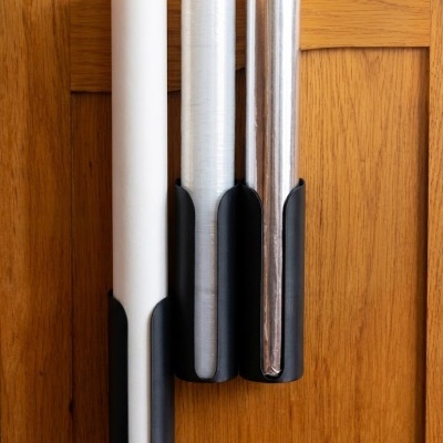 Três rolos de película em suportes pretos na porta de madeira clara de um móvel