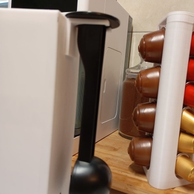 Máquina de café branca com alavanca preta e cápsulas de café em suporte branco