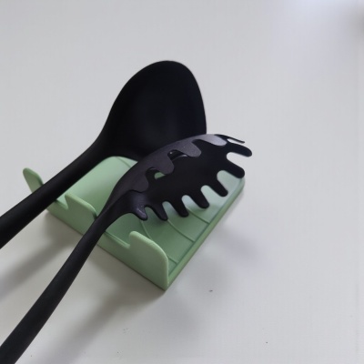Utensílios de cozinha pretos em nylon numa base verde clara