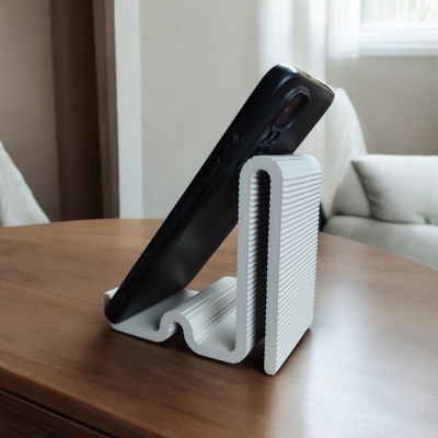 Suporte de telemóvel branco com textura riscada a segurar telemóvel preto numa mesa de madeira