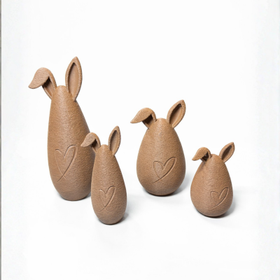 Quatro esculturas em forma de ovo com orelhas de coelho e coração gravado, castanhas com textura rugosa
