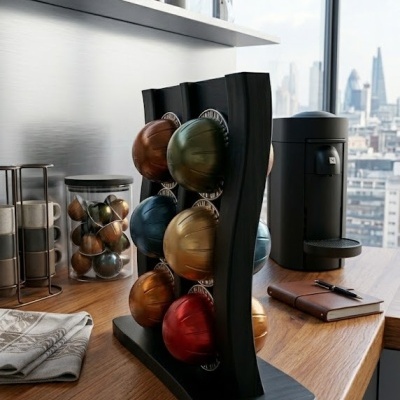 Porta cápsulas de café plástico preto com cápsulas coloridas metálicas em bancada de madeira interior de cozinha