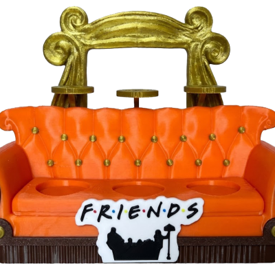 Sofá laranja aveludado com detalhes dourados e placa FRIENDS