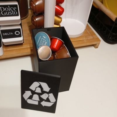 Recipiente preto com cápsulas de café coloridas e símbolo de reciclagem