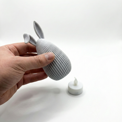 Vela LED branca e suporte cinza claro com orelhas, fundo branco.